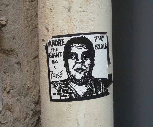 Un adesivo originale di Andre the Giant Has a Posse incollato su un palo, segnato dall'usura della strada