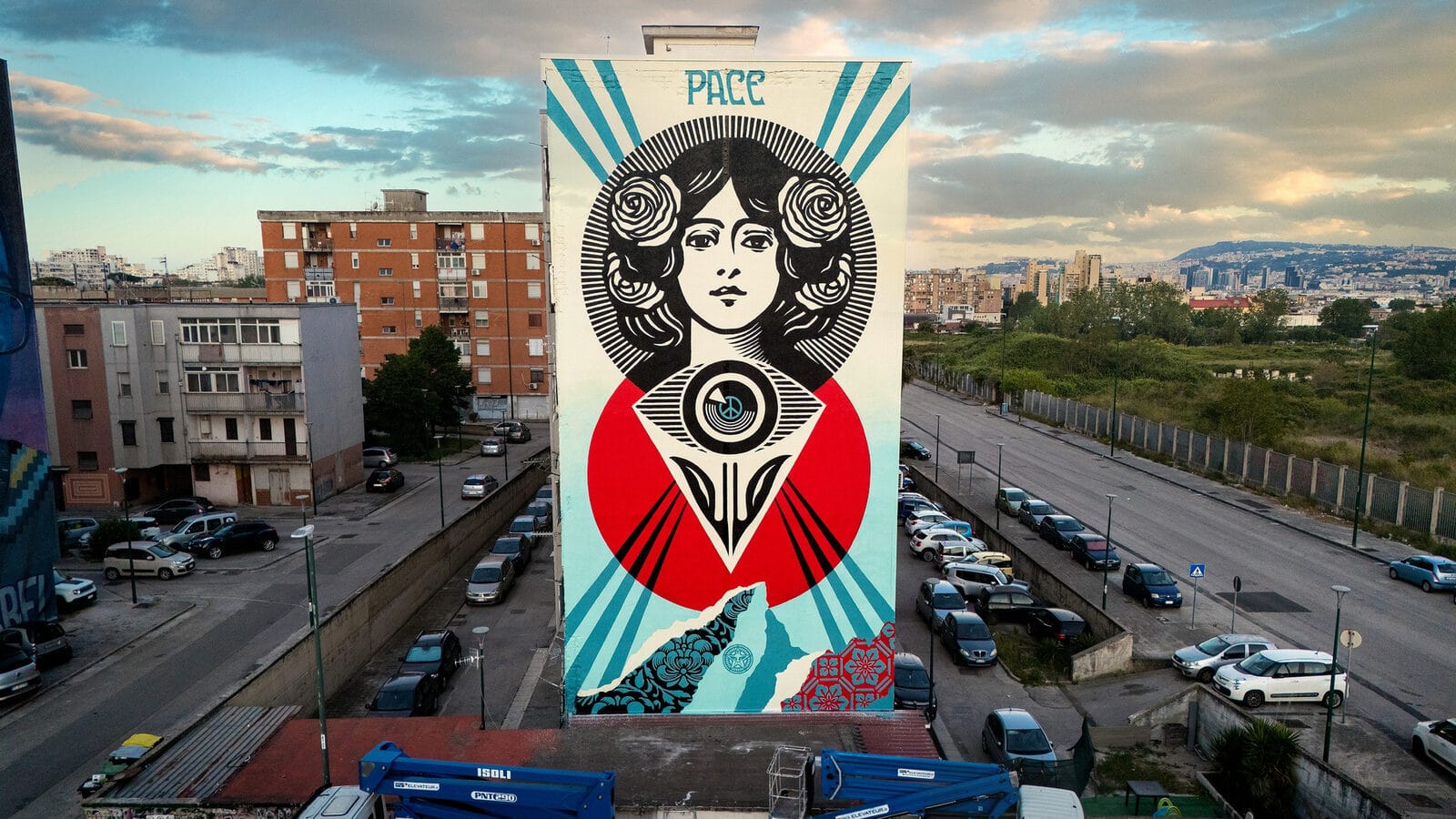 Pace, murale di Shepard Fairey a Napoli, Ponticelli, 2026: una donna con rose tra i capelli, un grande occhio centrale, e la scritta PACE in alto, su una parete laterale di un palazzo periferico