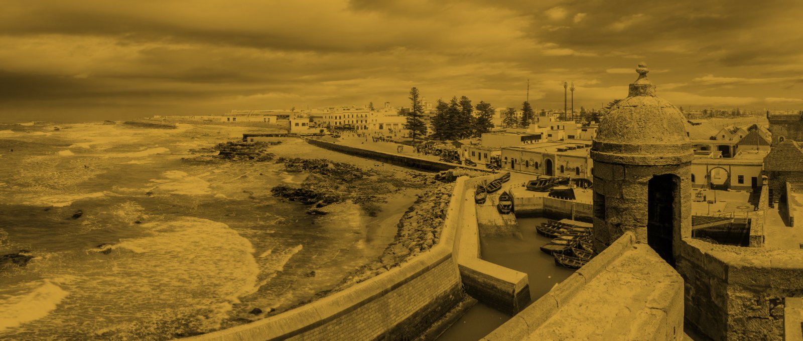 Les remparts marins d'Essaouira vus du bastion, en duotone doré : l'océan à gauche, la médina et le port à droite